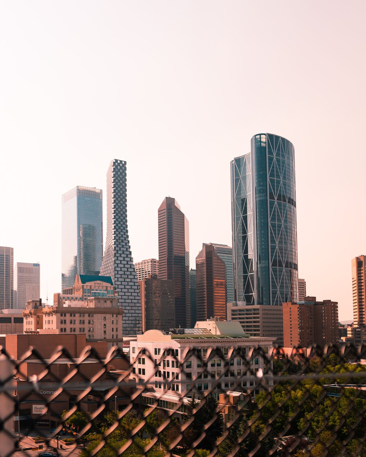Downtown Calgary skyline at dusk, viewed through a foreground fence