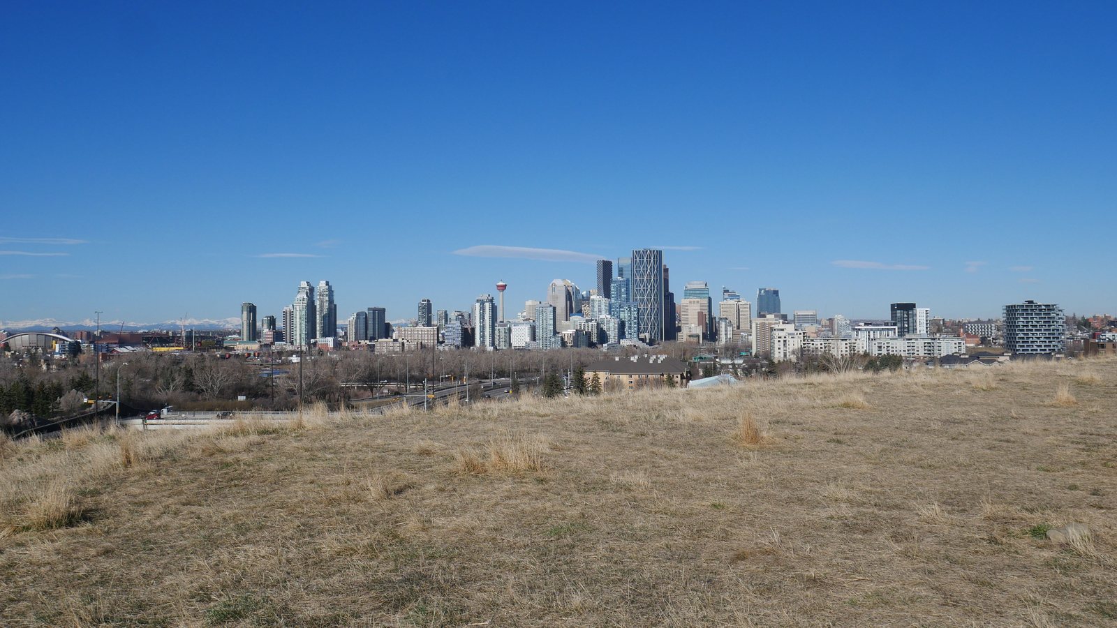 Calgary skyline and the Rocky Mountains beneath a clear blue sky